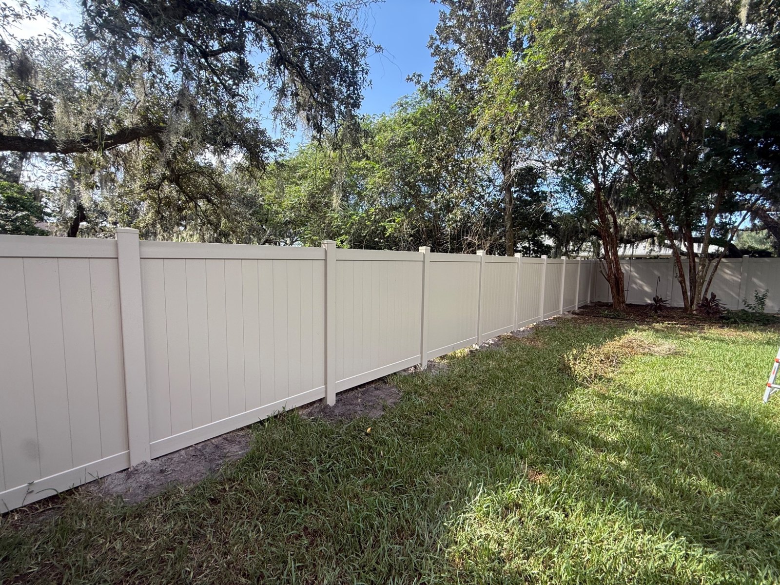White vinyl privacy fencing alongside a green lawn