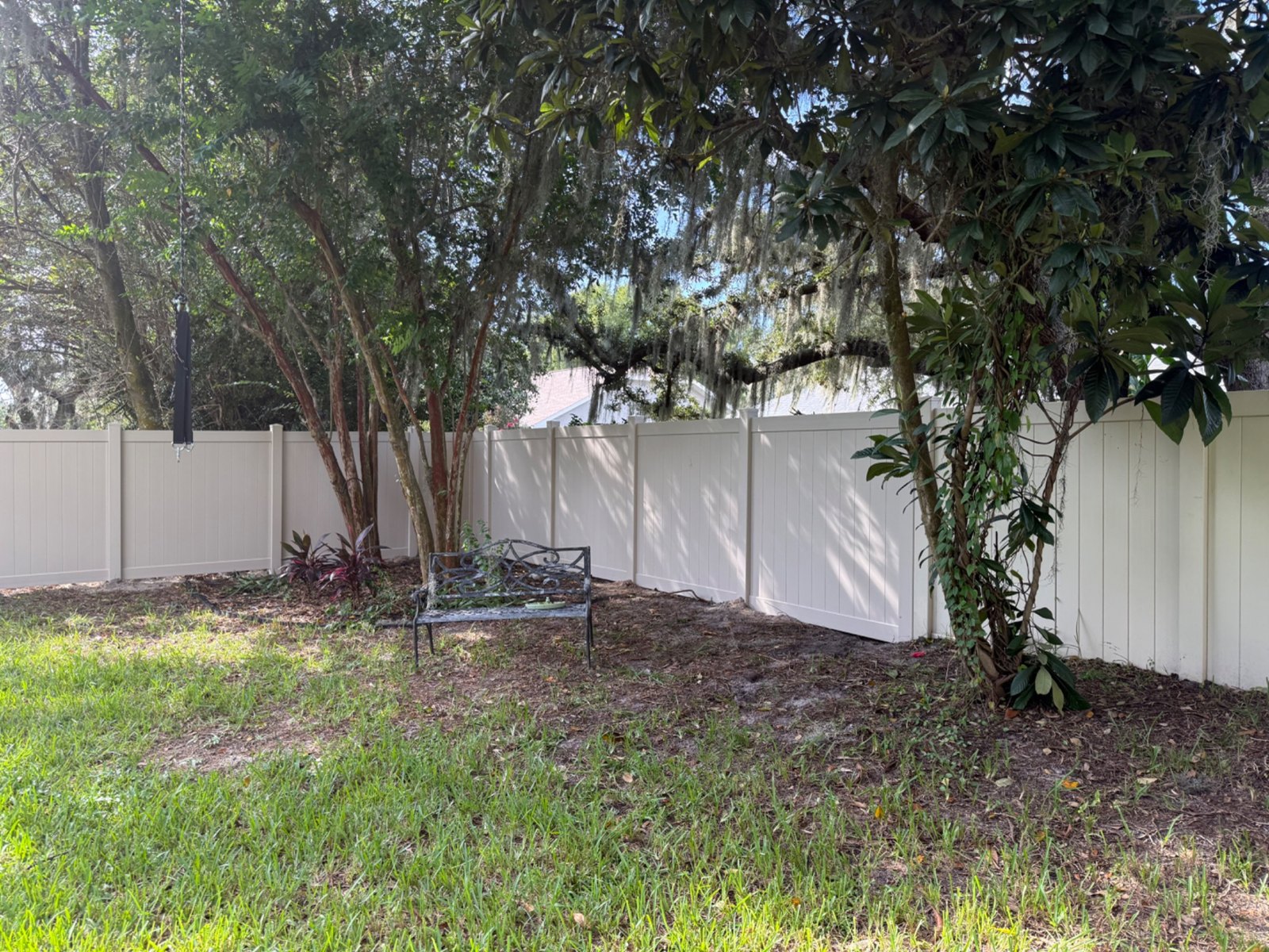 White vinyl fencing around a shaded backyard