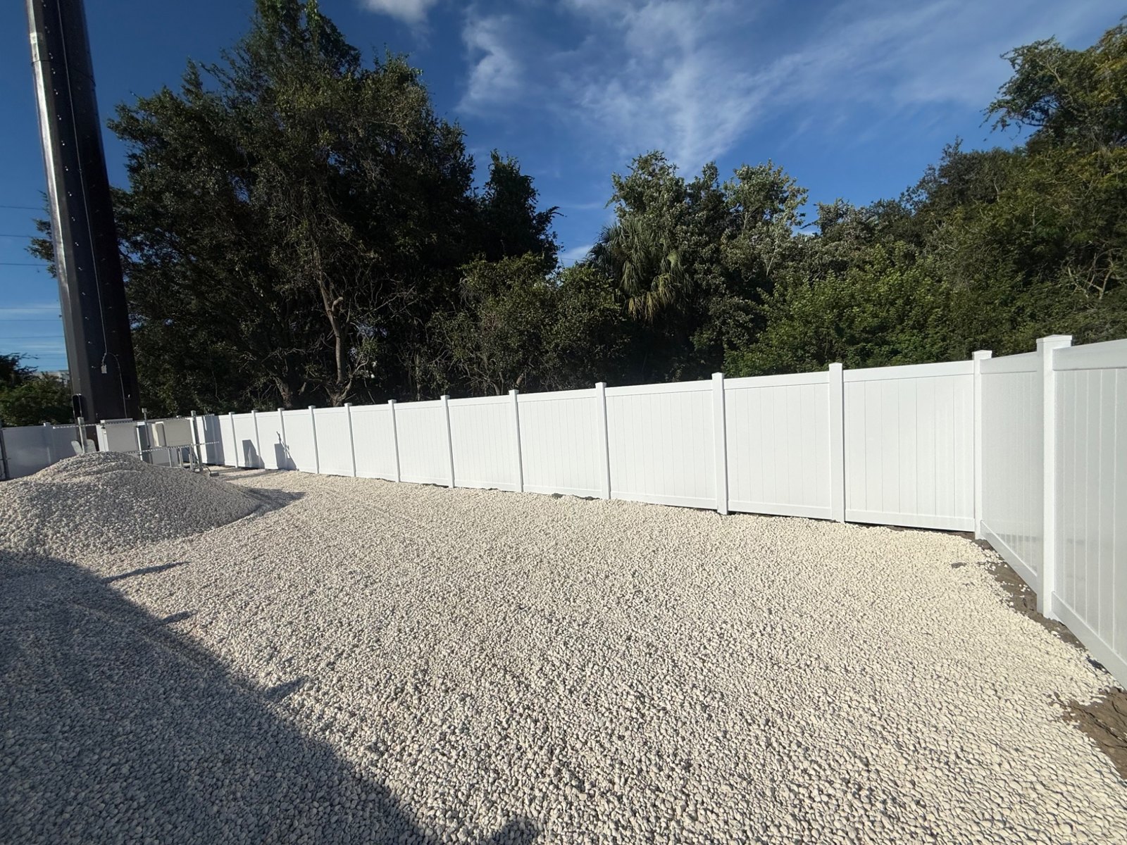 White vinyl perimeter fence with trees