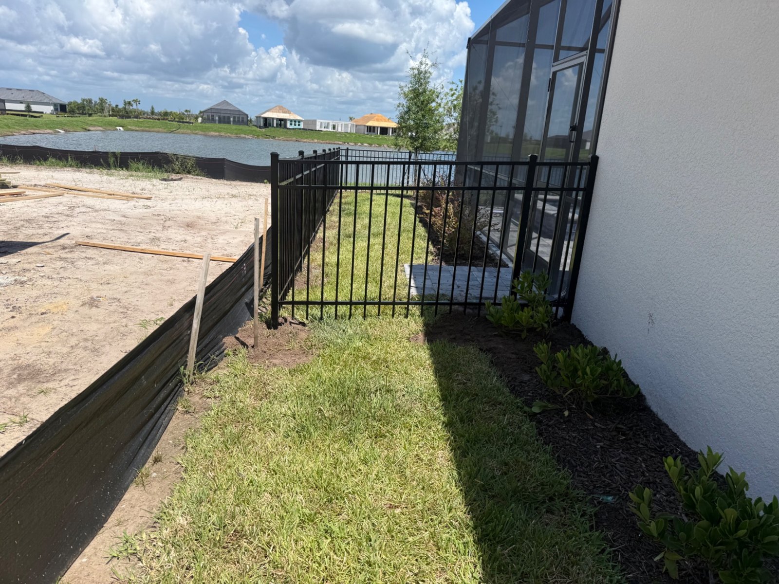 Black aluminum gate beside a screened patio