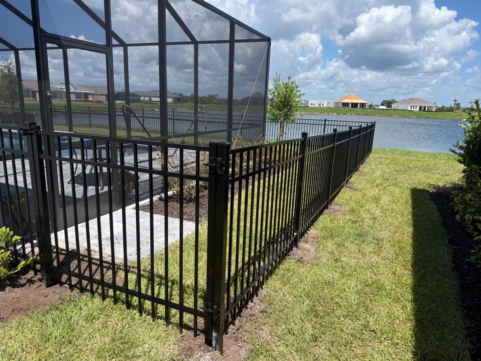 Black aluminum fence beside a screened patio and waterfront lawn